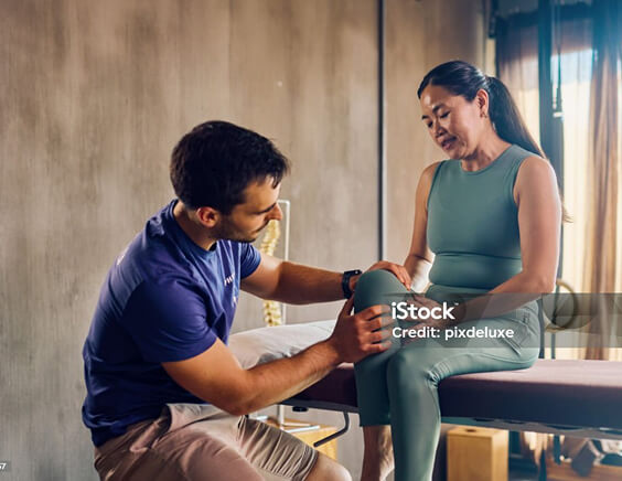 A doctor examining a woman's knee