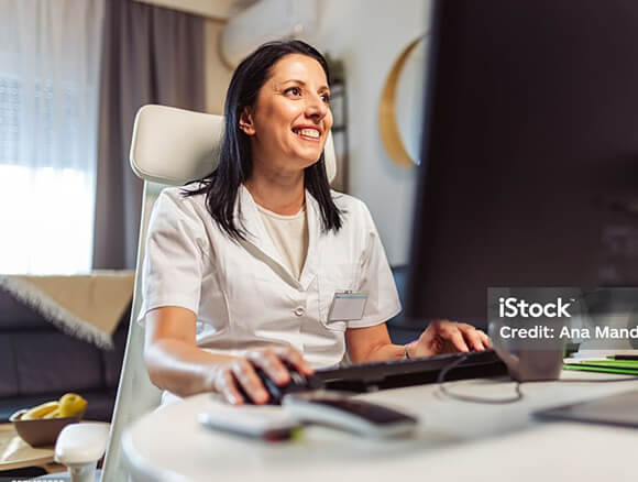 Photo of a medical specialist working on a computer, smiling.
